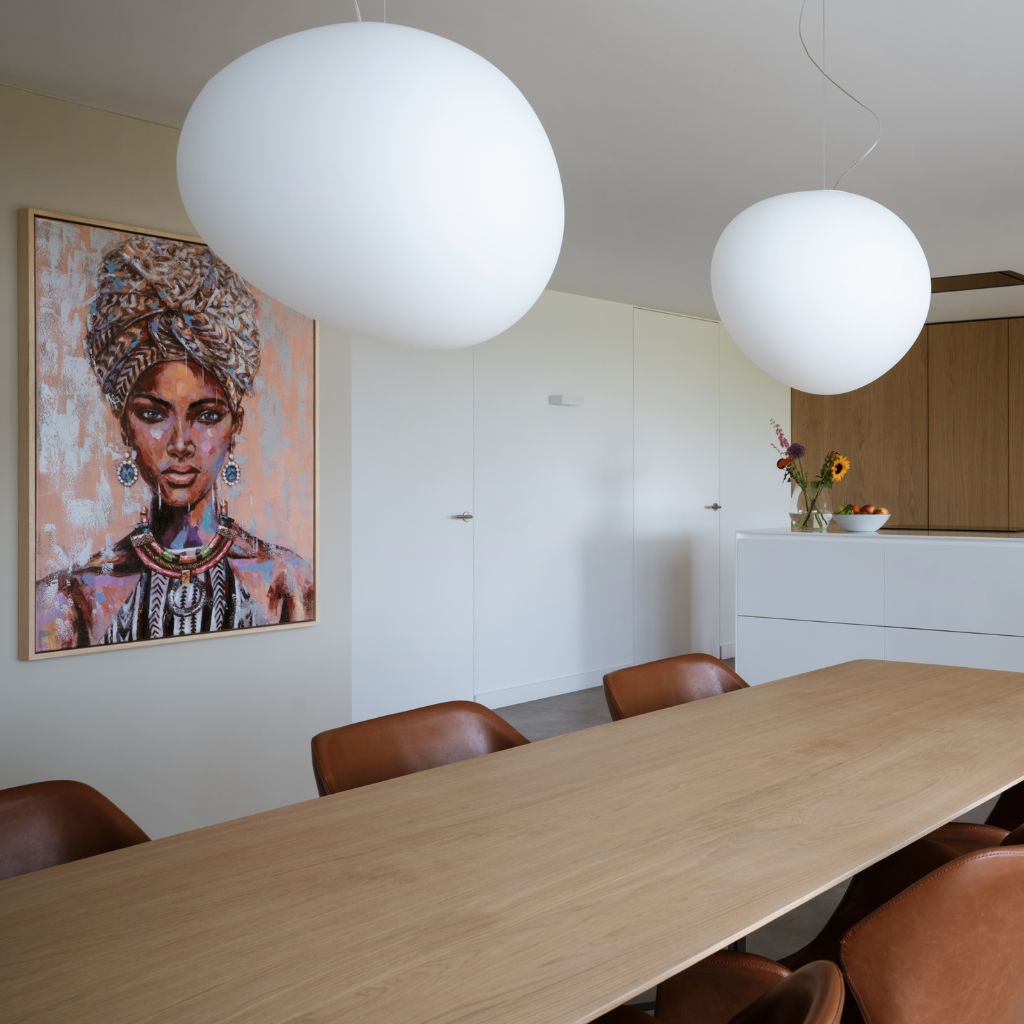 Eikenhouten eettafel met schilderij op de muur en witte hanglampen