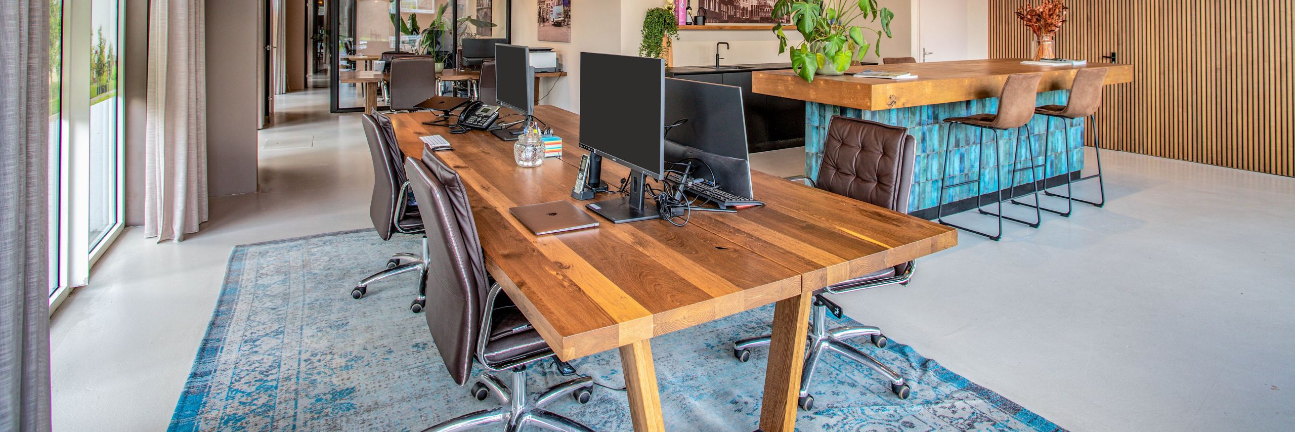 Kantoor met grote houten tafel voor meerdere werkplekken